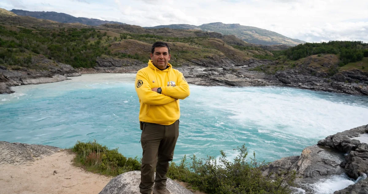 Pablo Espinosa Guerra, instructor de montaña, junto a un río de aguas turquesas en un entorno natural.